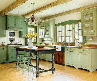 Green farmhouse-style kitchen with a wood island table and hanging chandelier